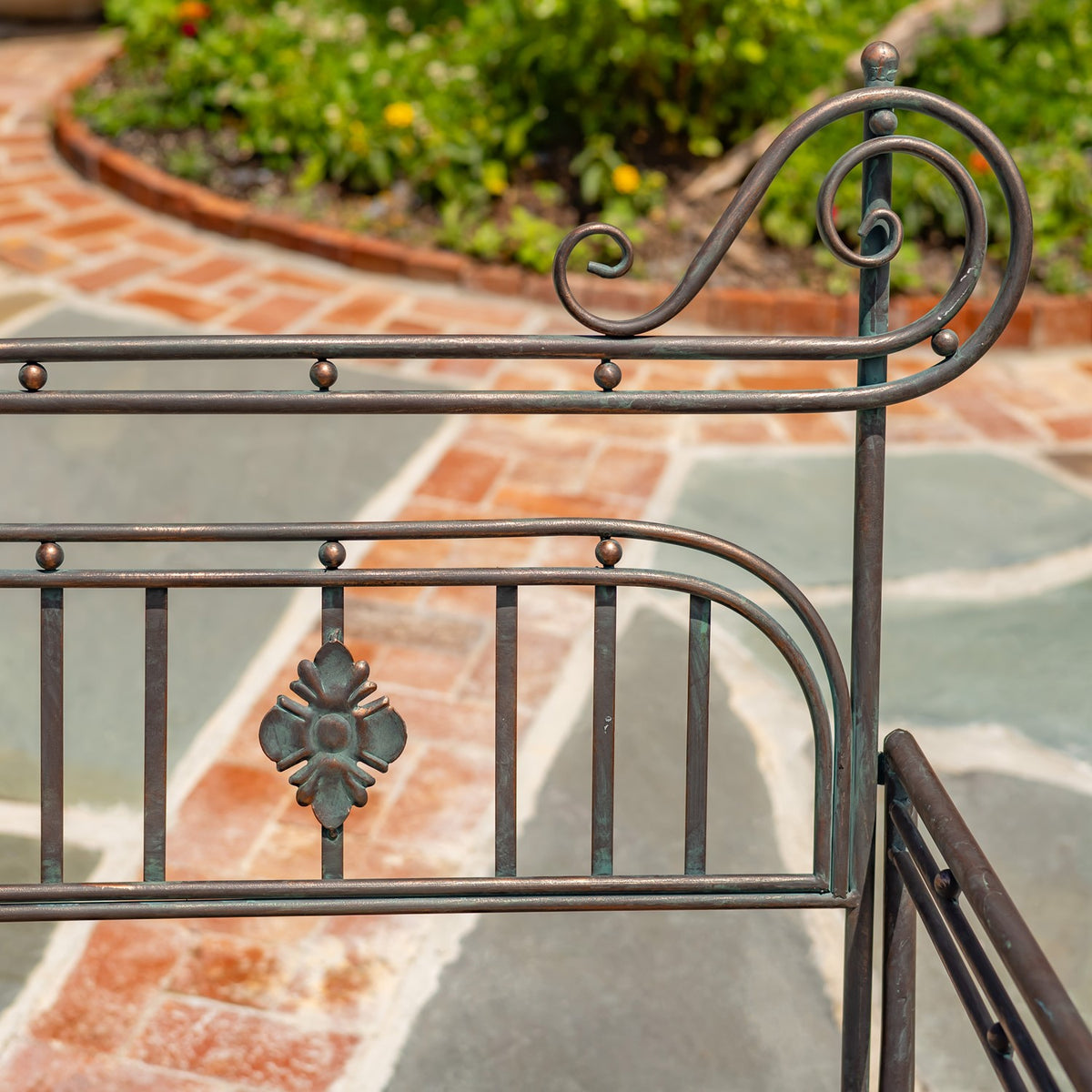 Close-up of the bench’s dark metal side frame, with curled scrollwork and decorative bars.