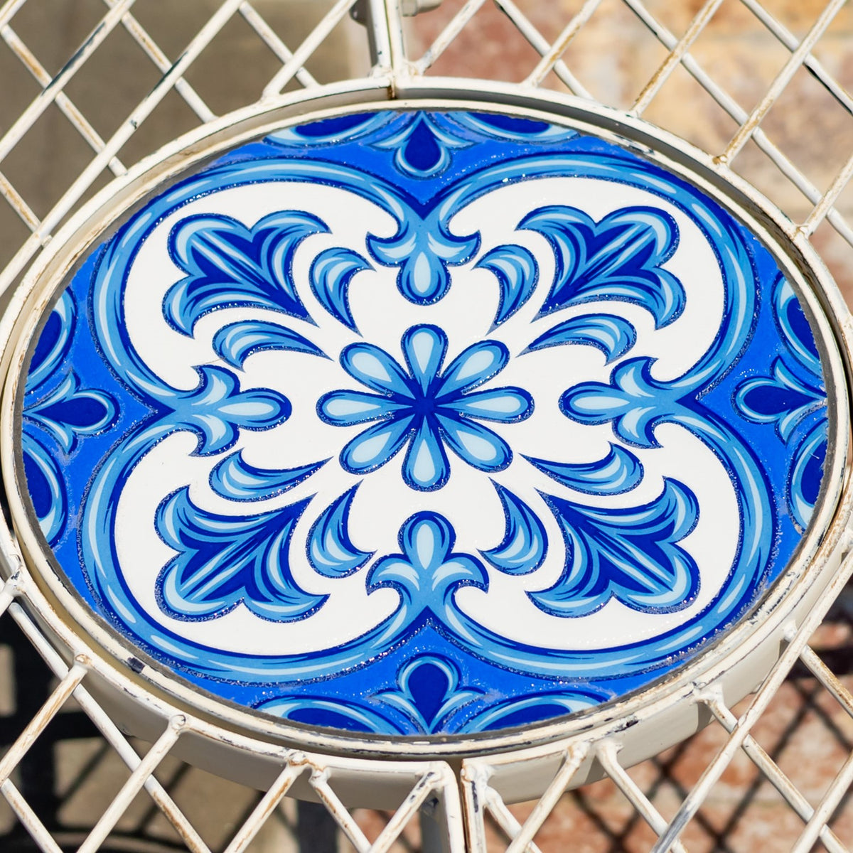 Overhead close-up of a round blue-and-white floral mosaic set into the bench’s metal seat.