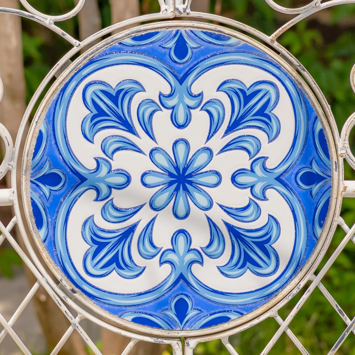 Round blue-and-white floral mosaic tile framed by ornate pale metal scrollwork.