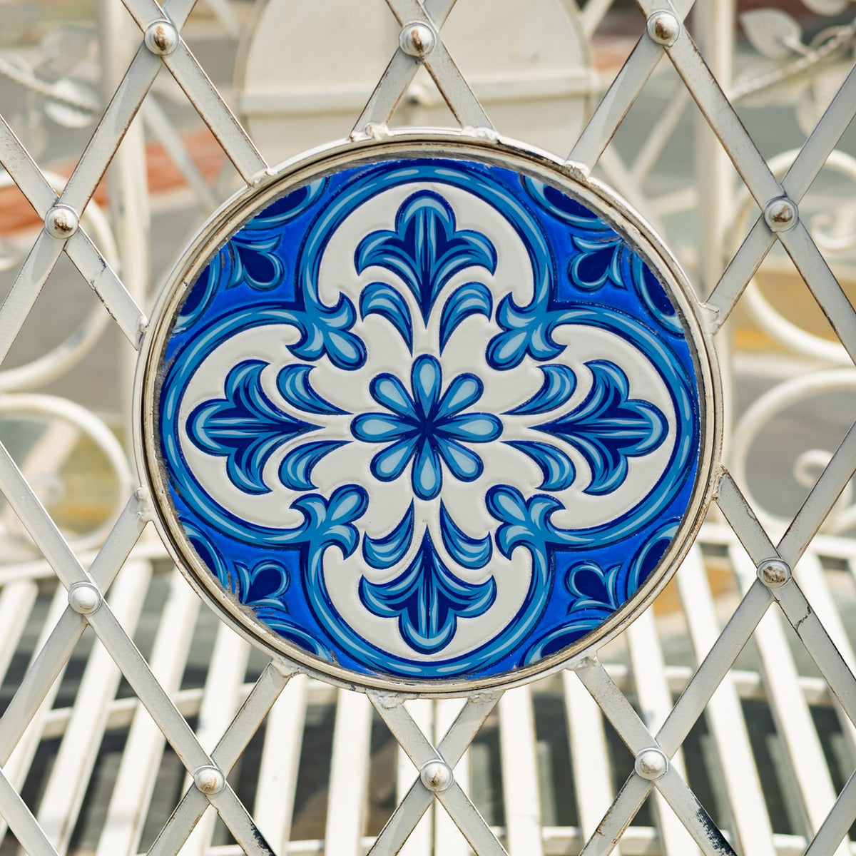 Round blue-and-white floral mosaic medallion set within a pale metal lattice.