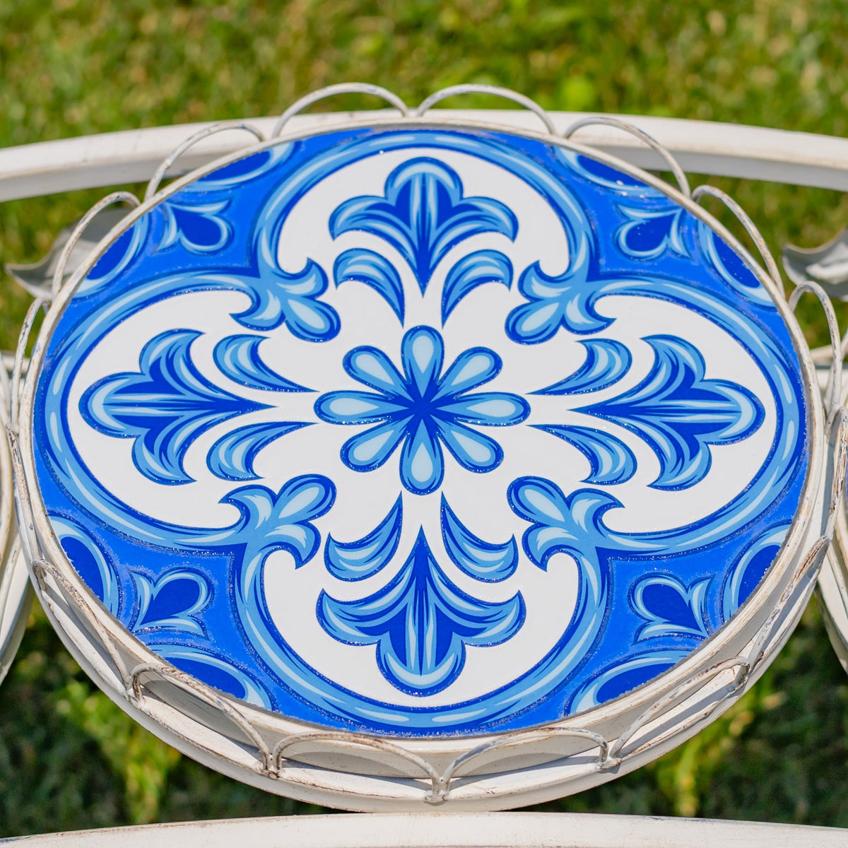 A round blue-and-white floral mosaic fills the tray, bordered by a curved metal rim.