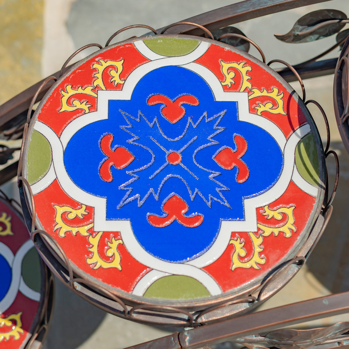 Overhead close-up of a round mosaic surface with a blue, red, white, and green pattern.