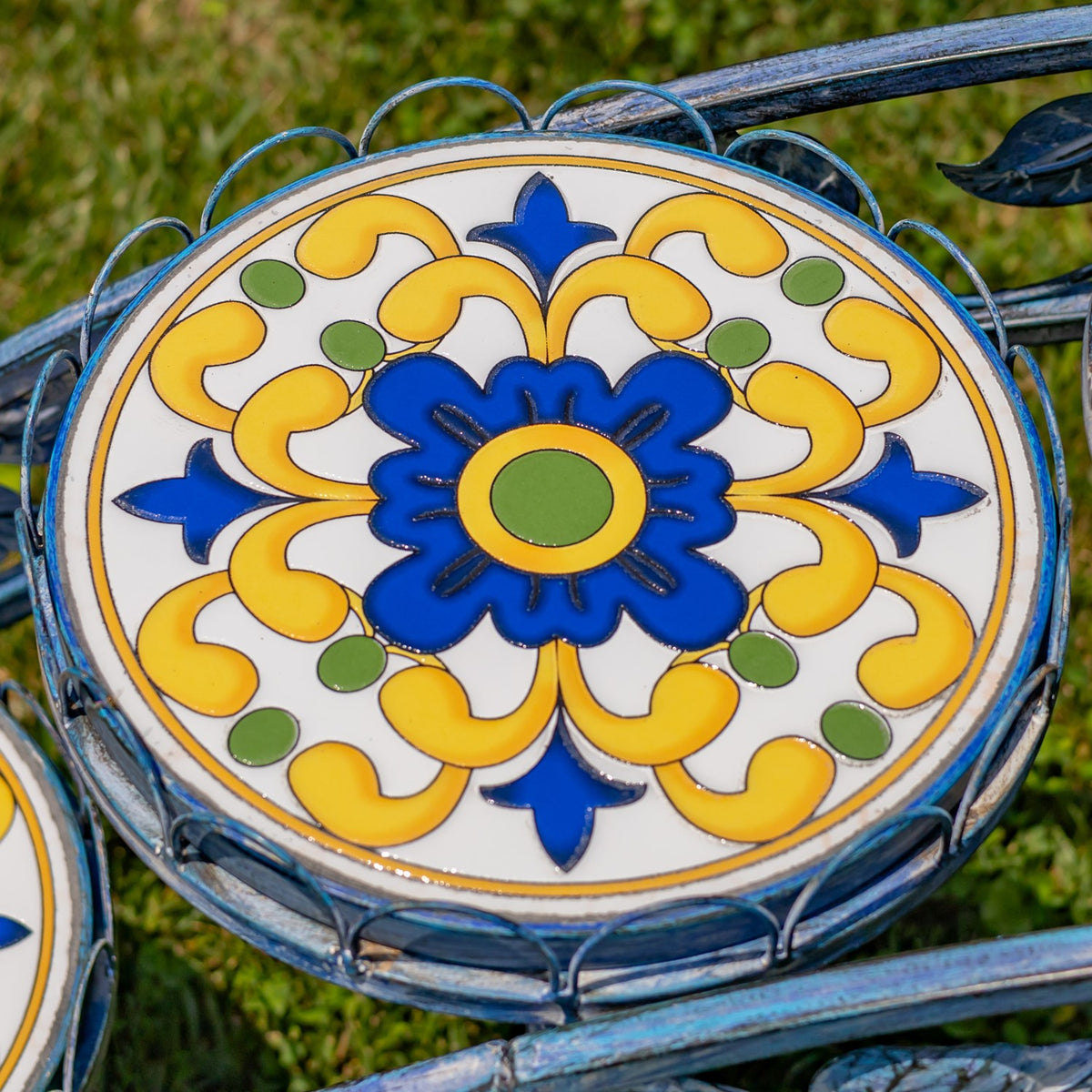 Round tabletop with a blue flower and yellow, green, and white mosaic pattern.