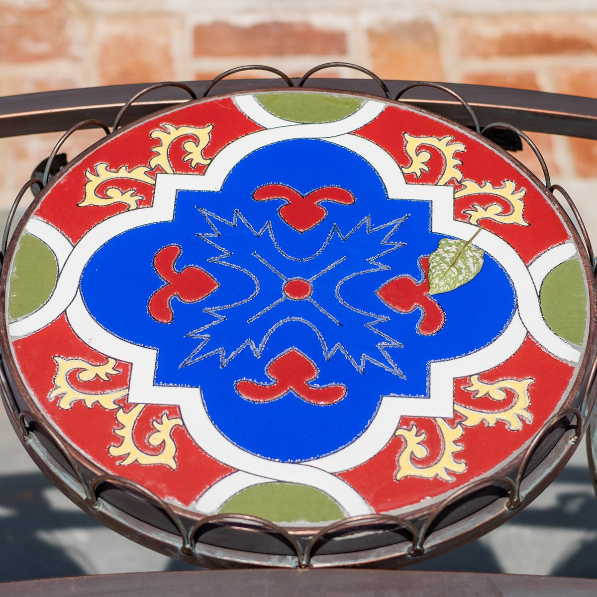Overhead close-up of a round mosaic top with a bold blue, red, white, and green pattern.