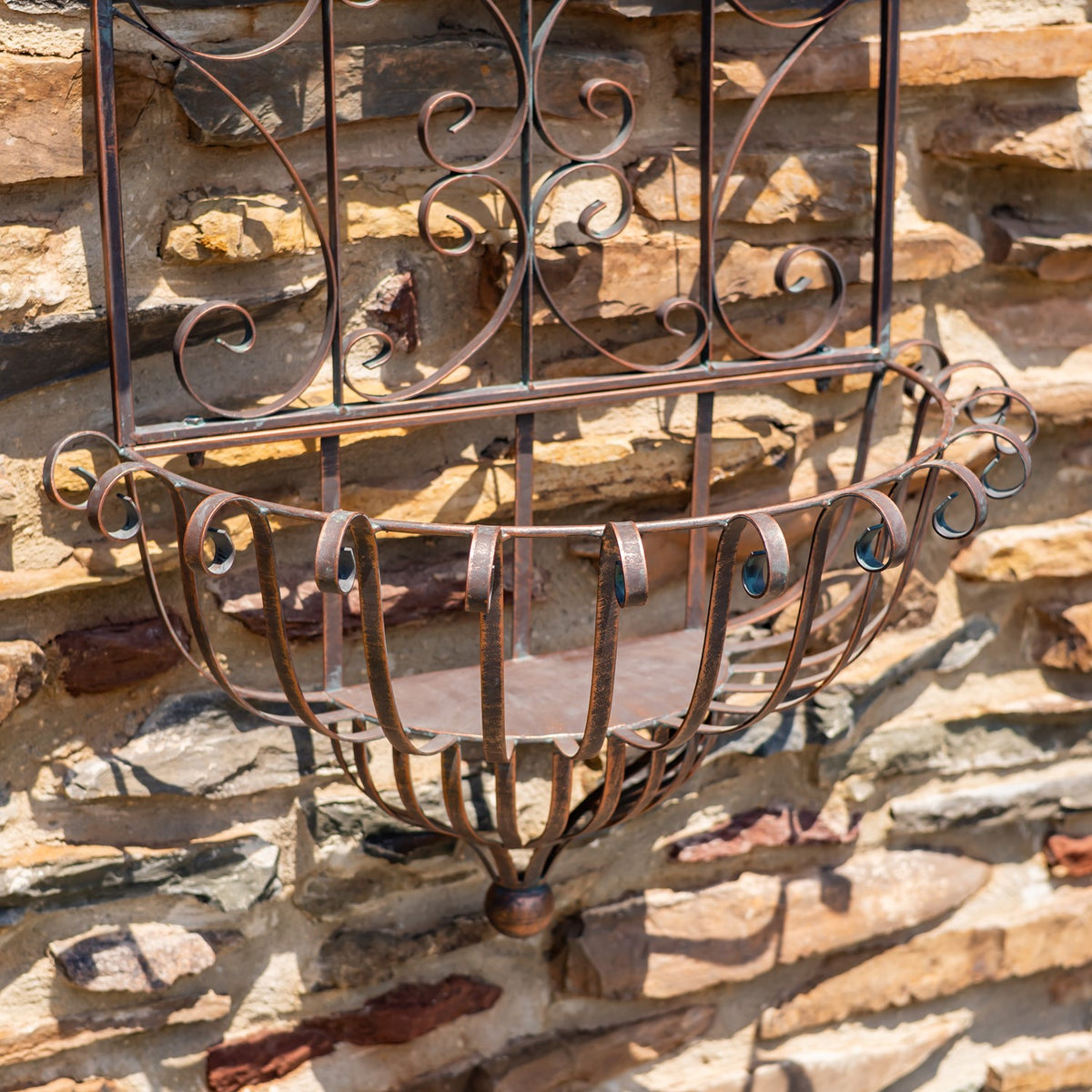 Close-up of the curved, scrollwork metal basket beneath the planter’s decorative frame.