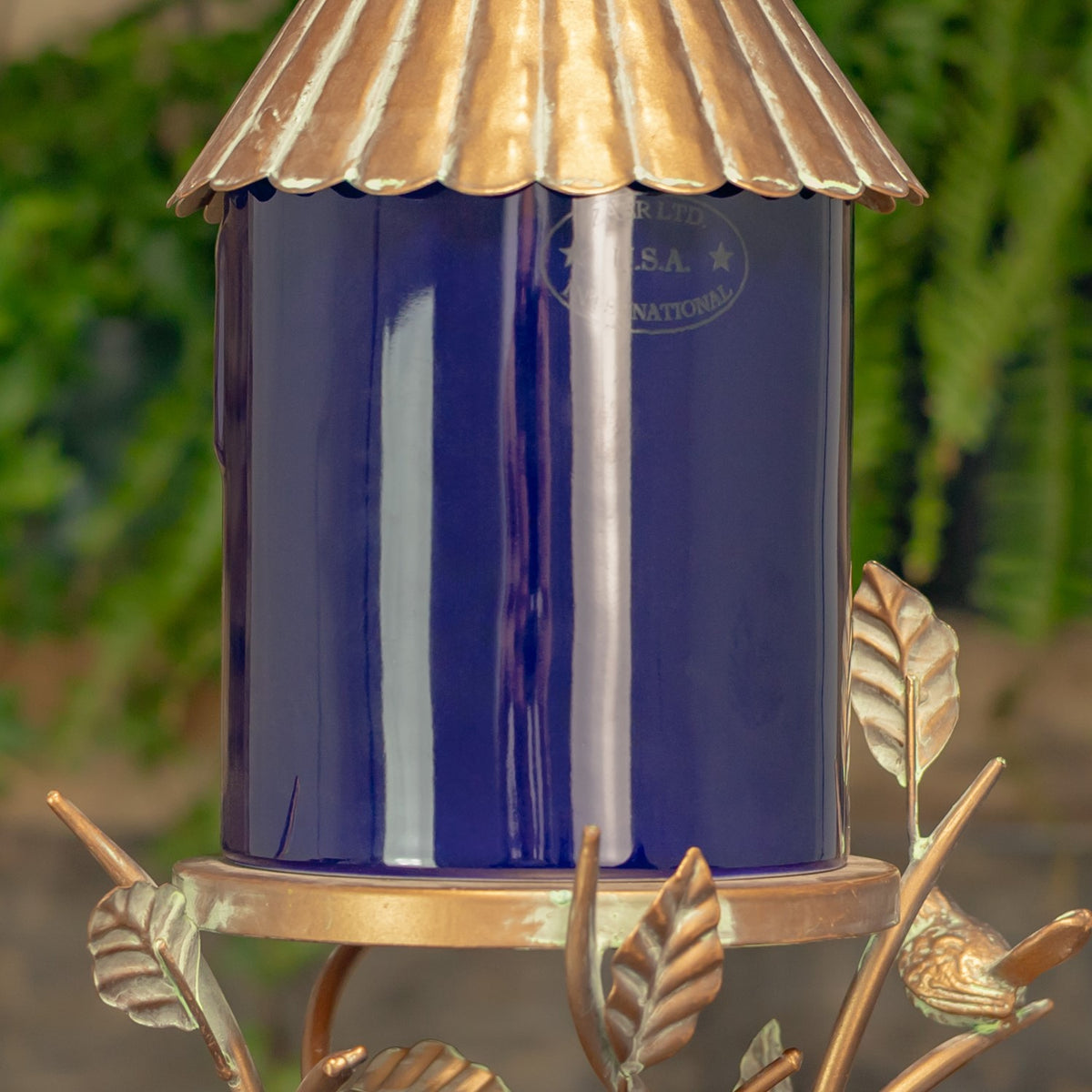 Glossy blue birdhouse body above a metal perch, with leaf and bird-shaped accents.