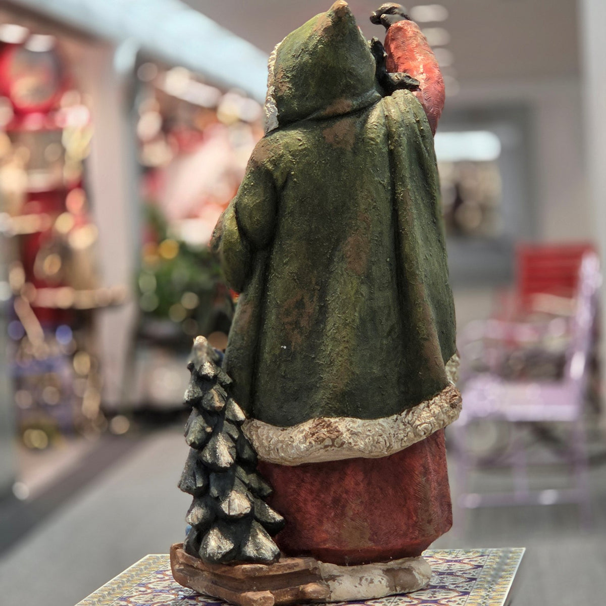 Back view of the multicolor Santa figurine with a tree at its side