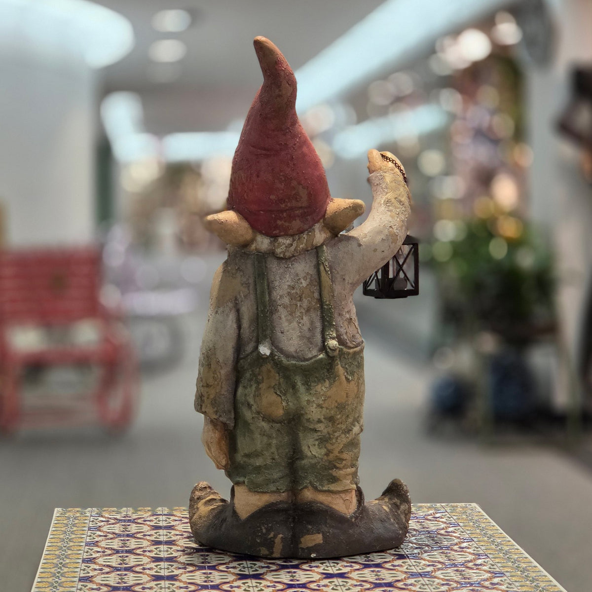 Rear view of a rustic garden gnome holding a black lantern