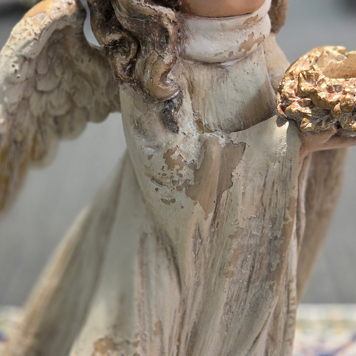 Detail of the angel figurine's distressed robe, wing and gold-toned bouquet