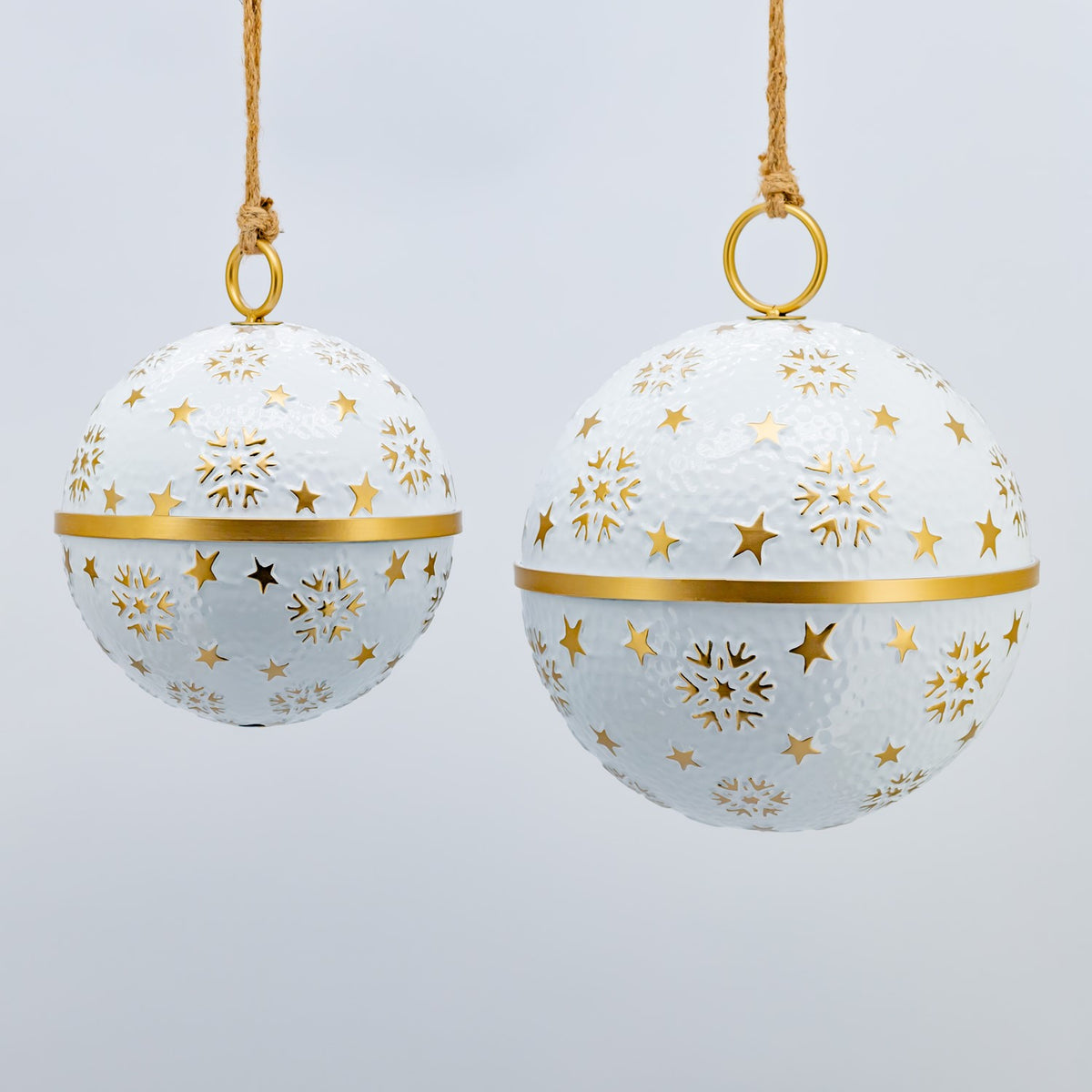 A pair of white and gold patterned ornaments hangs side by side, with the larger bauble on the right.