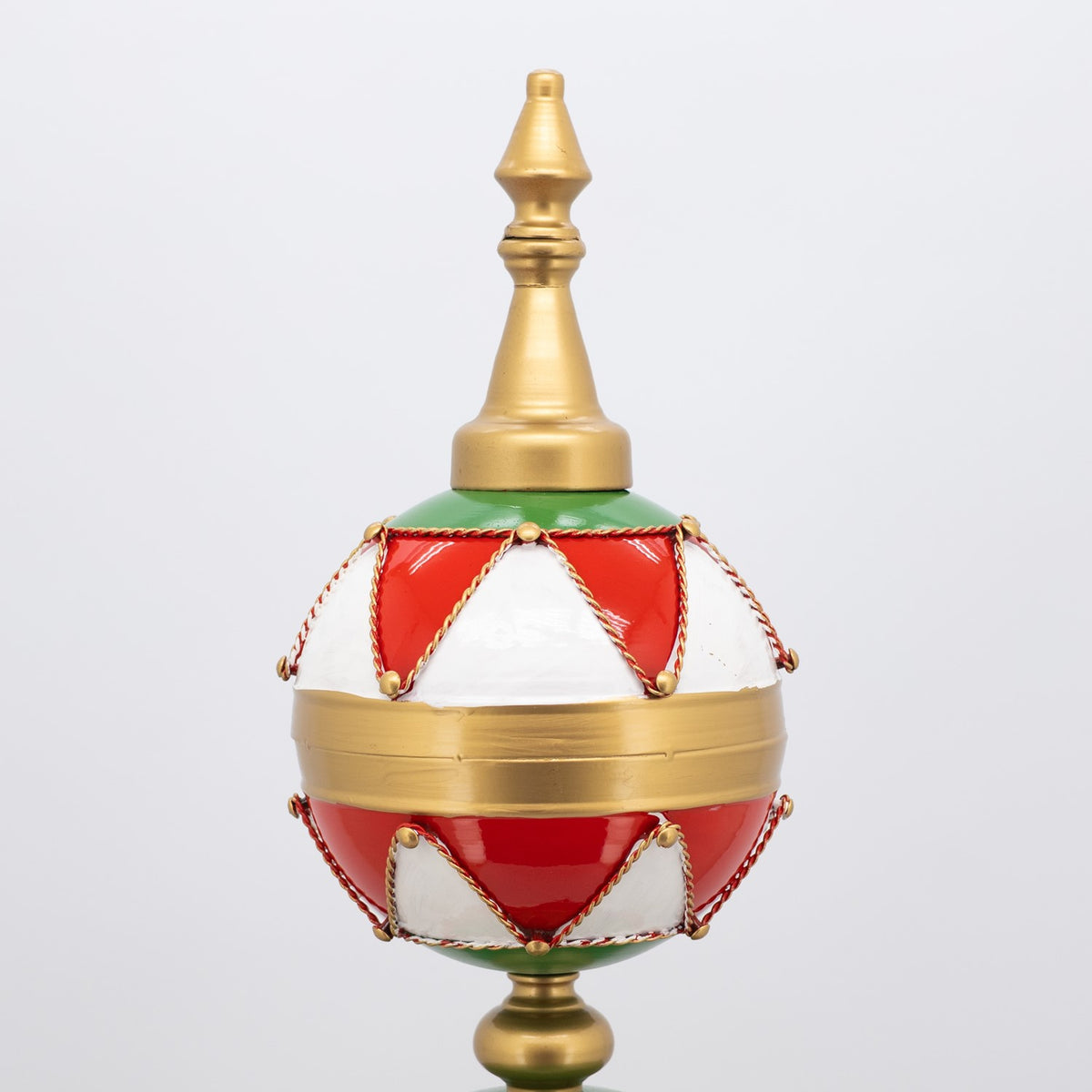 Close-up of a red and white bauble with gold trim, braided cords, and a gold finial.