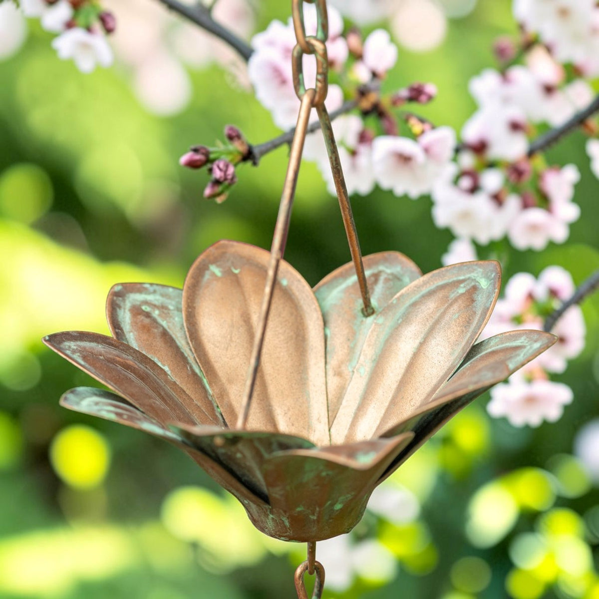 Close-up of a copper-toned flower cup with petal-shaped edges and linked chain.