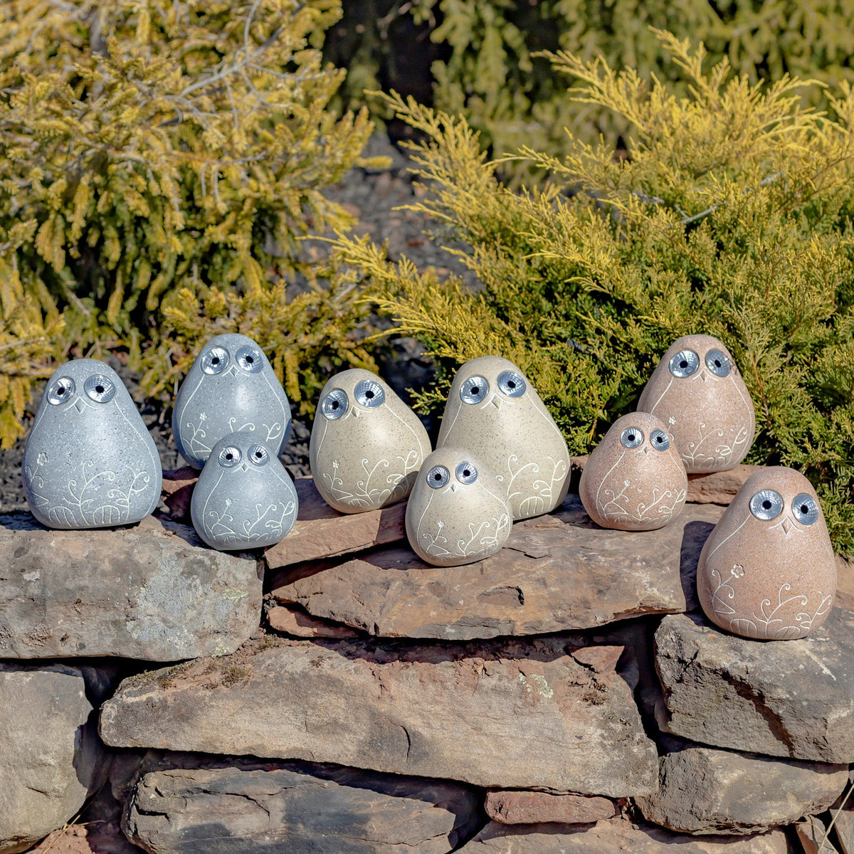 Tan and gray stone-look birds of different sizes are arranged across a stack of rocks.
