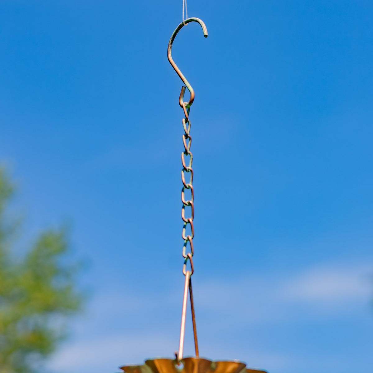 Curved hanging hook and linked rain-chain segments against a blue sky.