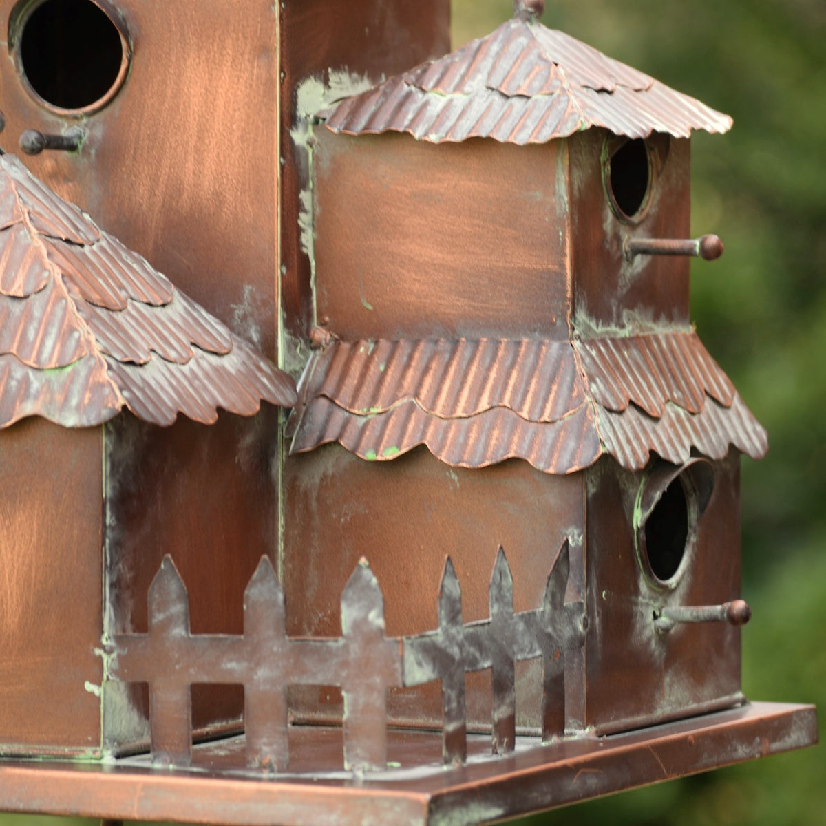 Close-up of corrugated metal roofs, round bird openings, projecting perches, and the miniature fence.