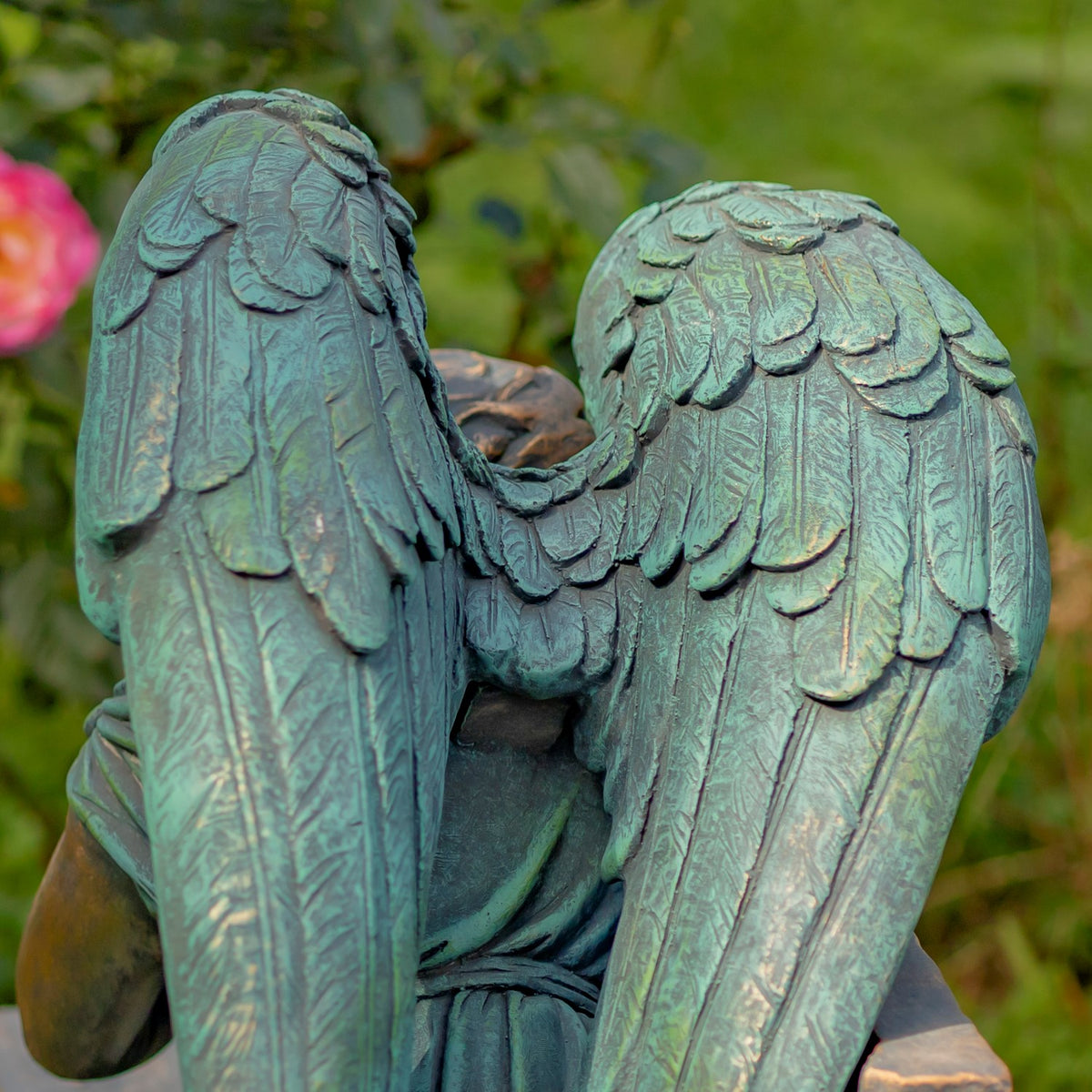 Close-up of the angel’s overlapping feather shapes and textured green patina across both wings.