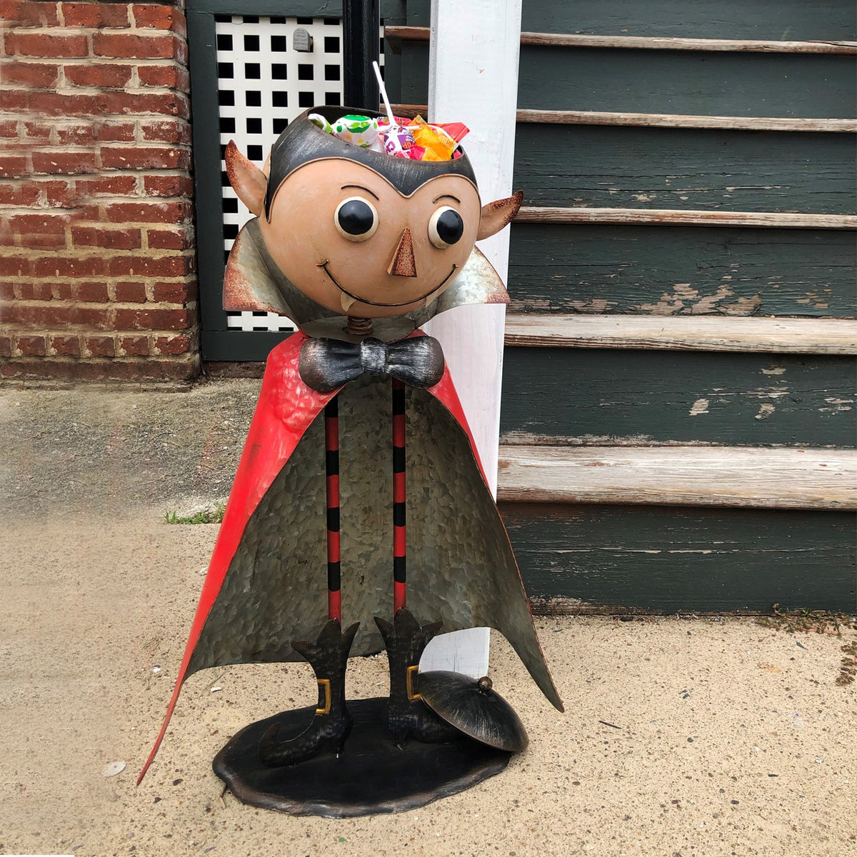Full view of the vampire figurine holding an open head lid filled with colorful wrapped candy.