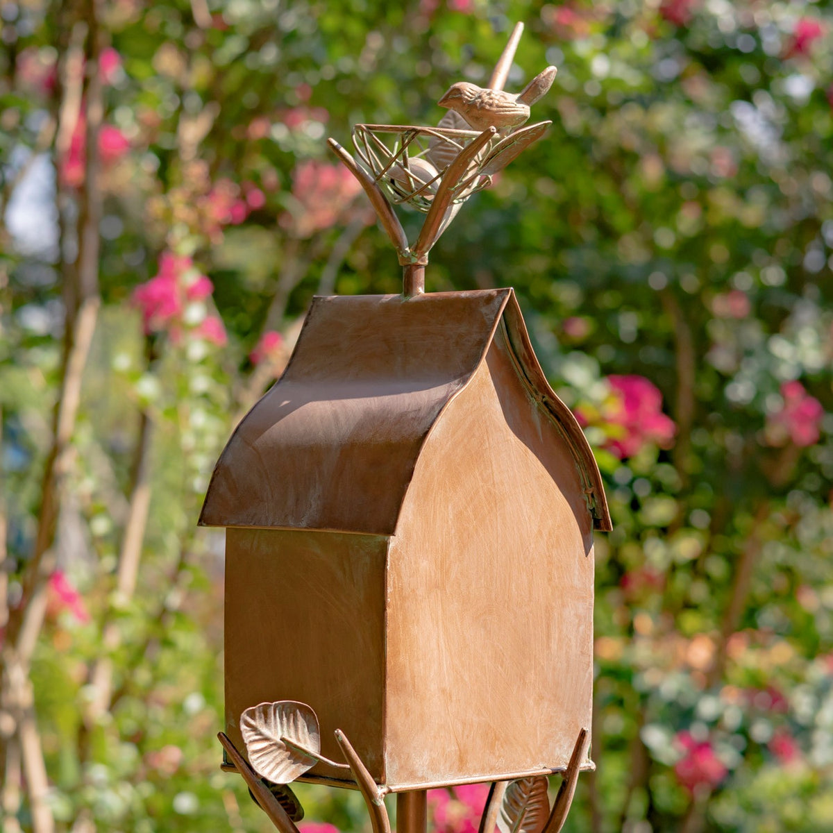 Angled view of the birdhouse showing its side panel, sloped roof, and decorative bird perched above.