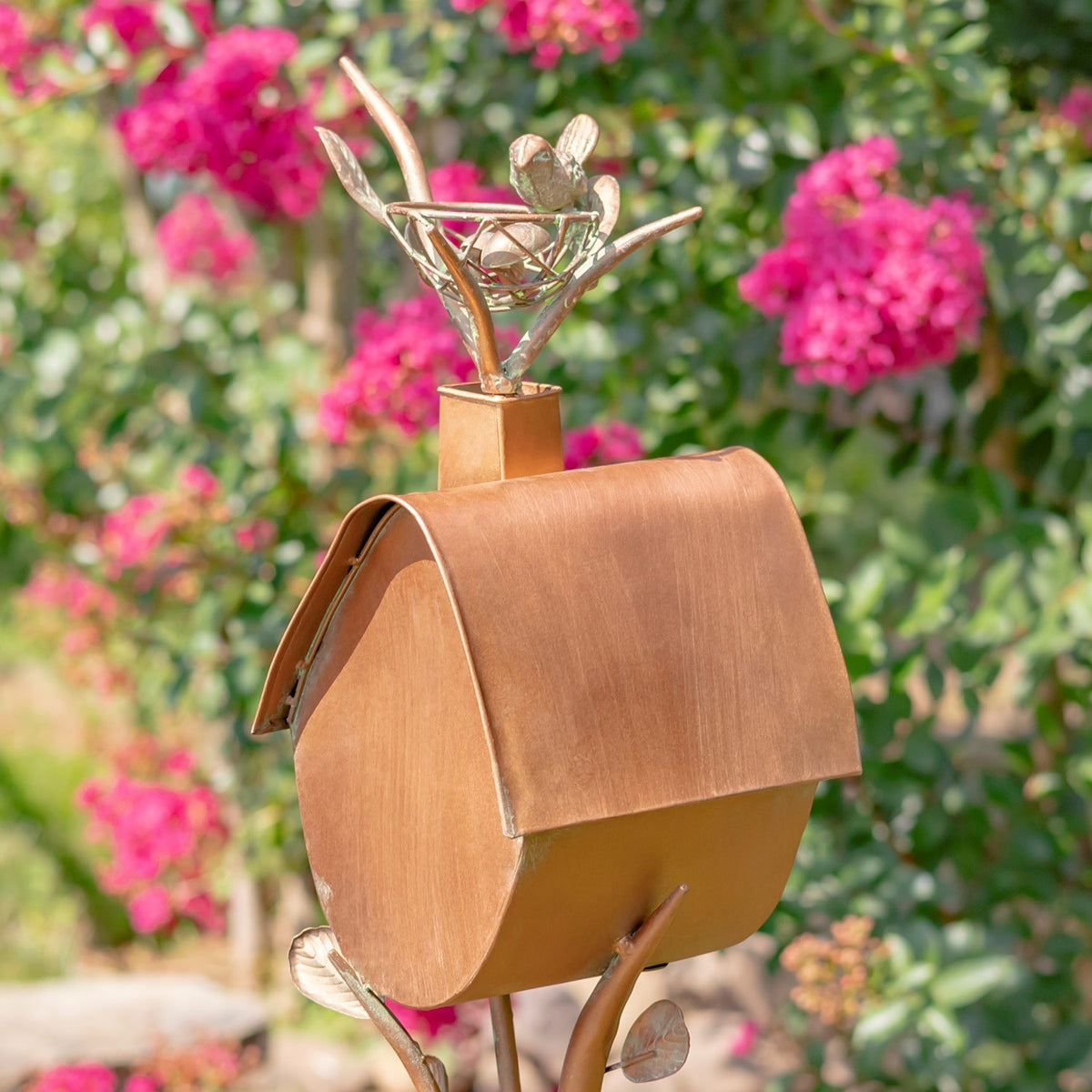 Angled view of the birdhouse showing its curved roof, rounded end, and leafy metal accents.