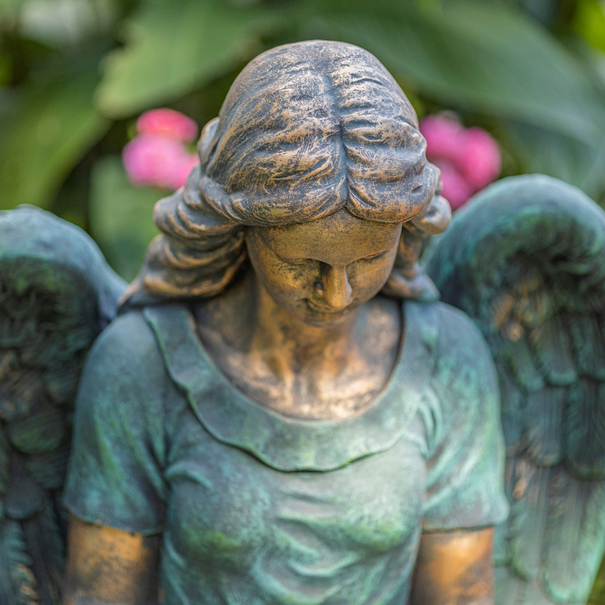 Close-up of the angel’s bowed head, wavy hair, and weathered teal clothing.