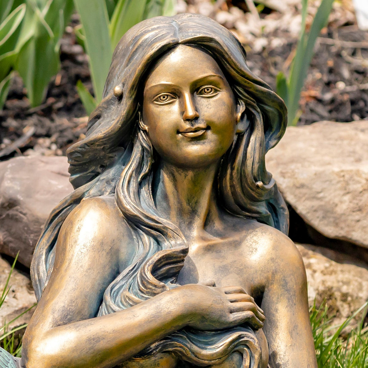 Close-up of the mermaid’s bronze-toned face, flowing hair and crossed arms.