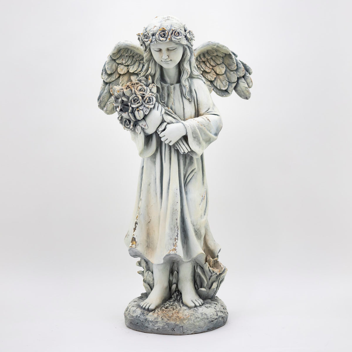Full-length view of the angel holding a bouquet, with outstretched wings and a sculpted floral base.