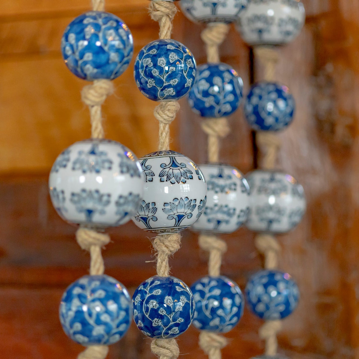 Angled view of glossy blue and white patterned balls with rope knots against a wooden wall.