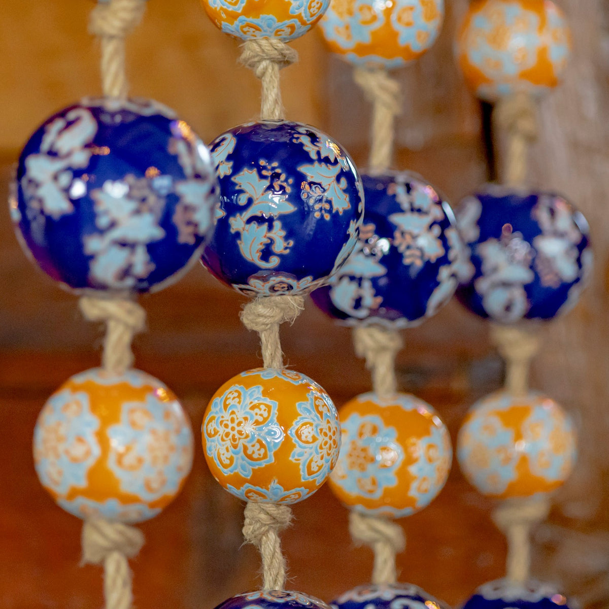 A blue patterned ball and an orange patterned ball in sharp focus among the hanging strands.