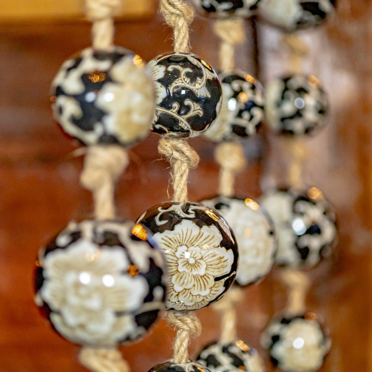 A close view of patterned ceramic balls and knotted natural-fiber cord, with other strands blurred behind.