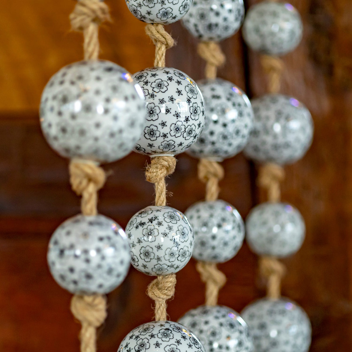 A close-up shows floral designs on glossy white balls and knotted tan cords.