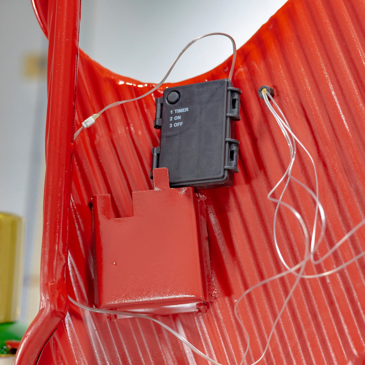 Close-up of the red archway backing with a black control box and white wires.