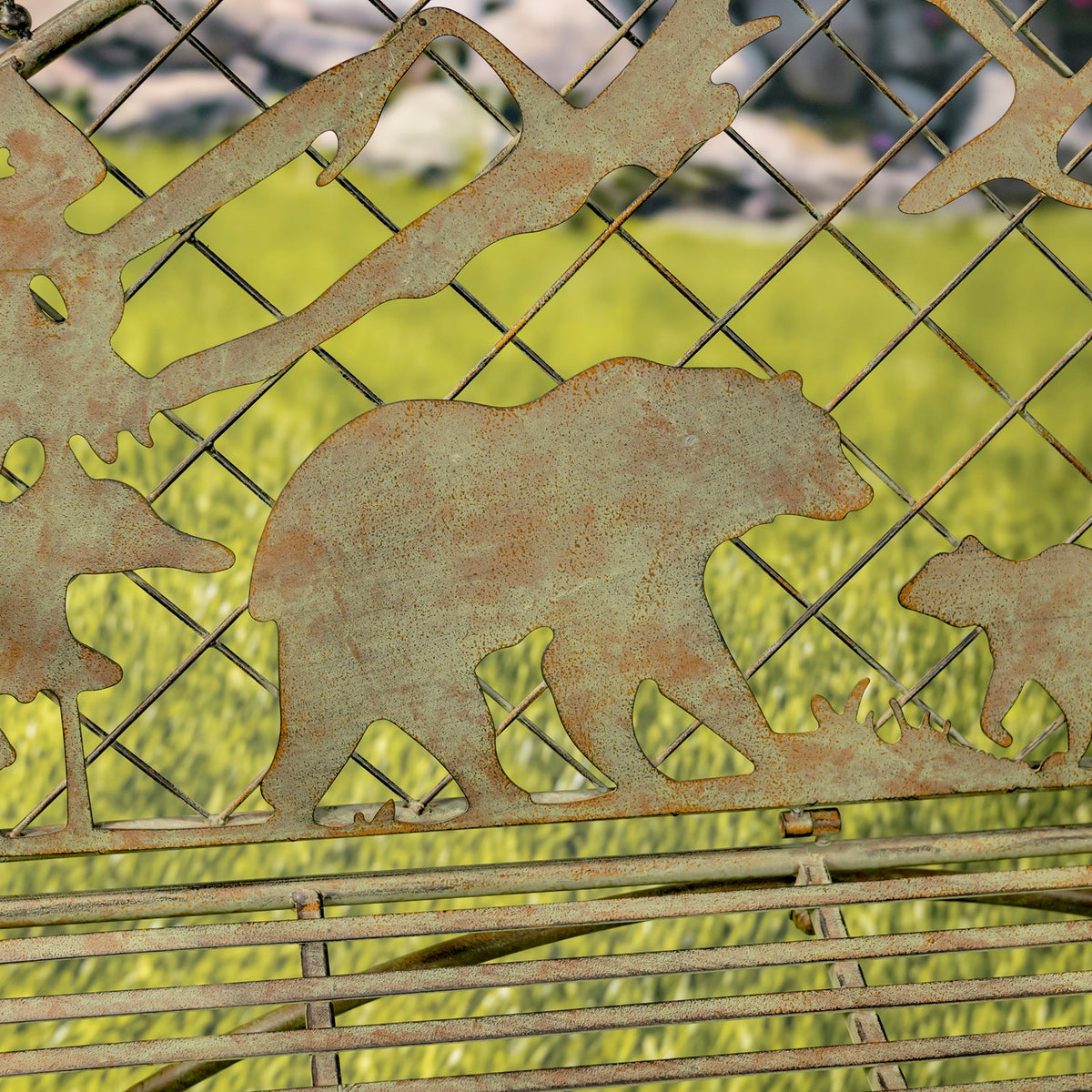 Close-up of a bear silhouette beneath mountain shapes against the bench’s metal mesh back.