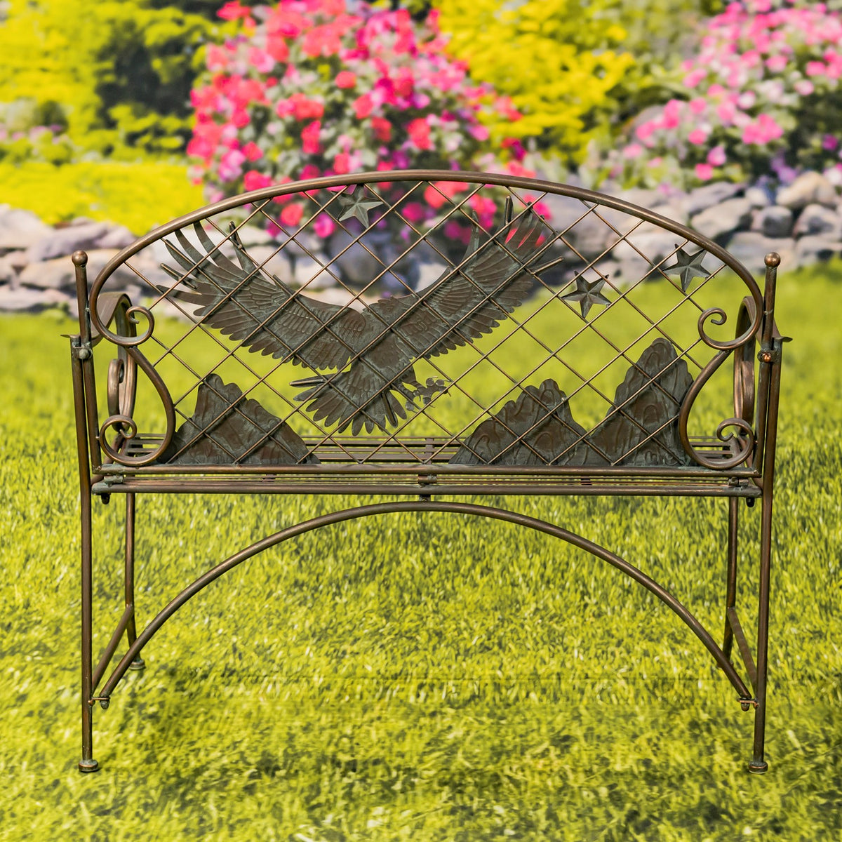 The full iron bench stands on grass, showing its arched eagle backrest, scrollwork, and curved legs.