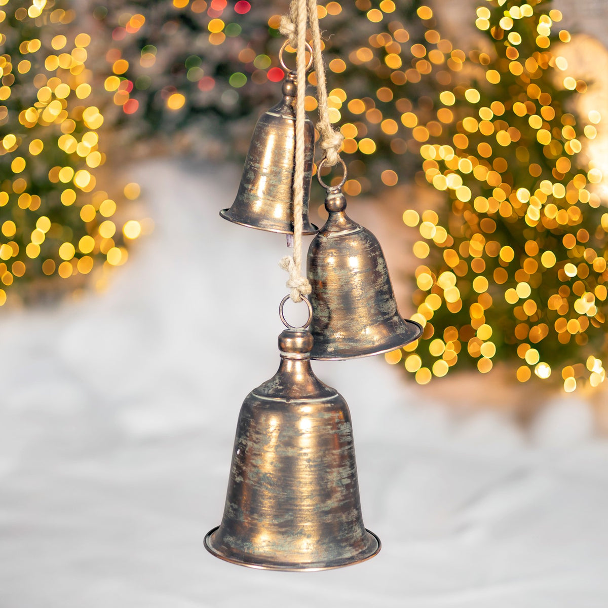 A large bell hangs in front of two smaller antique-gold bells, with their ropes visible.