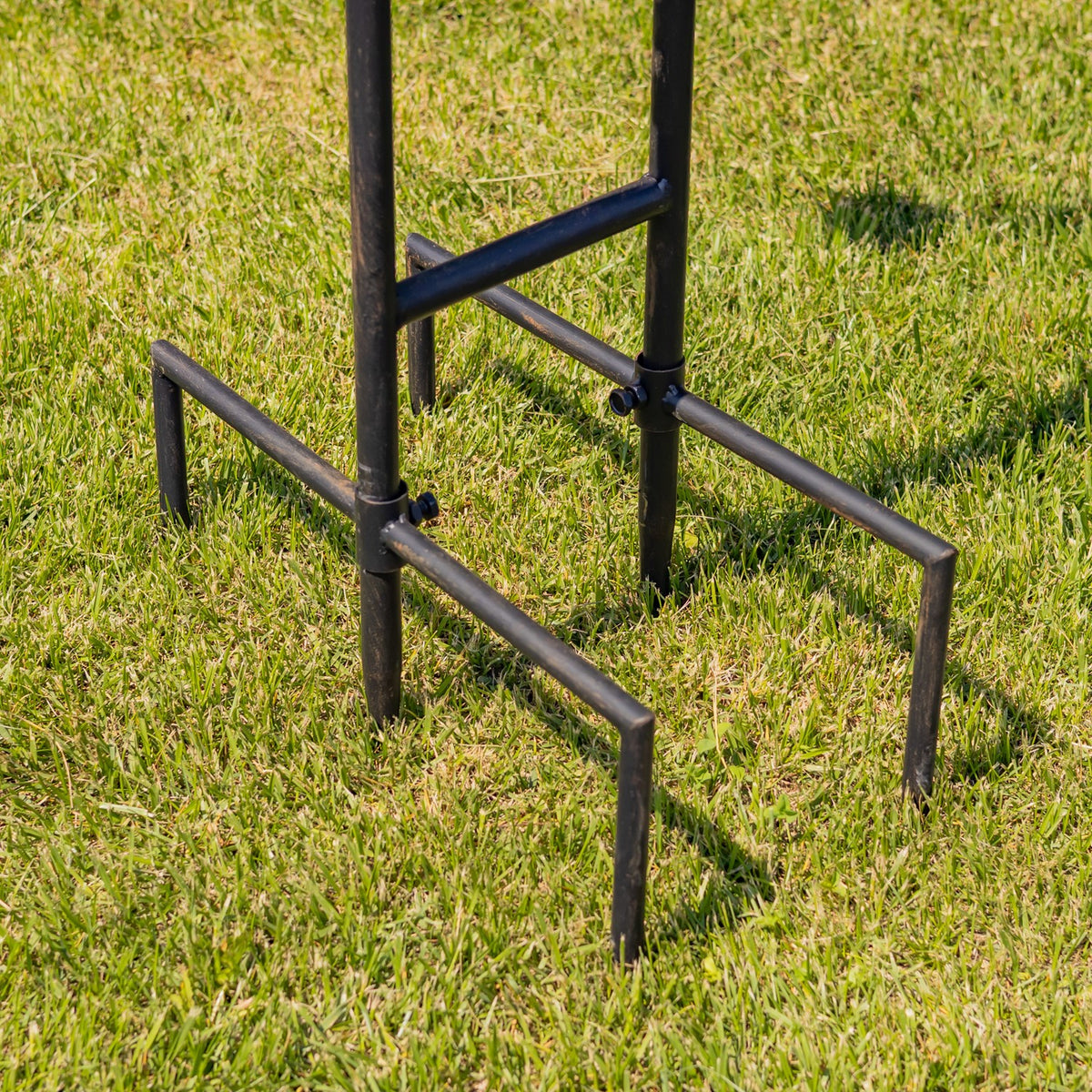 Close-up of the dark metal legs and crossbars planted in grass.