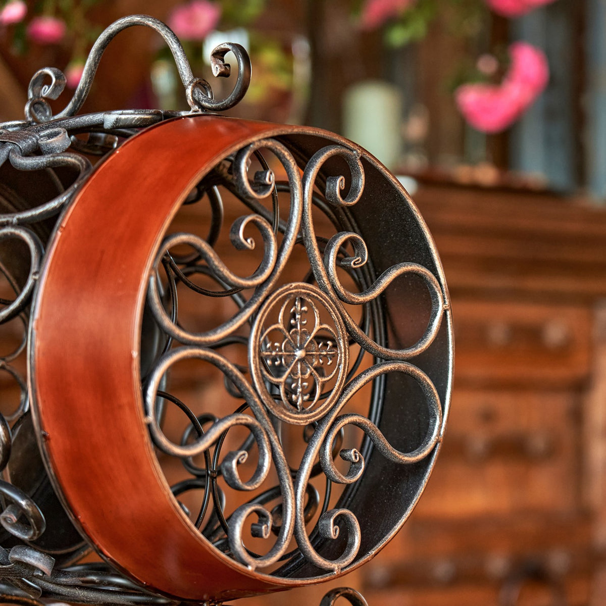 Close-up of the rack’s circular end panel, featuring raised scrollwork and a reddish-brown curved band.