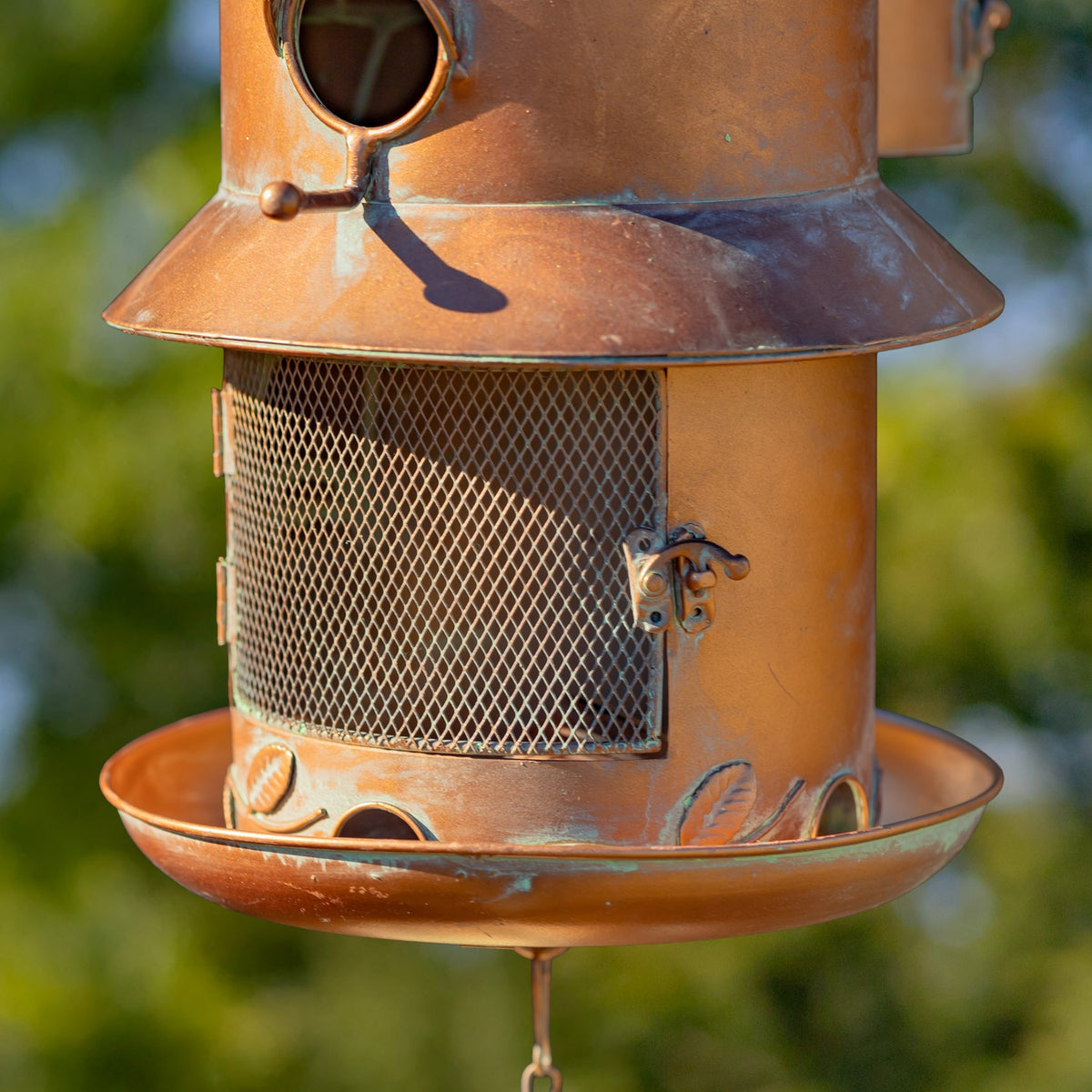 Close-up of the feeder's wire mesh panel, decorative latch and shallow tray.