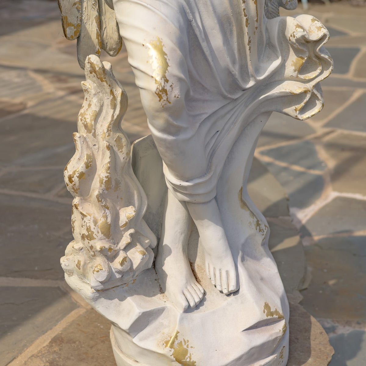 Close-up of the statue’s bare feet, flowing robe, and sculpted ornament on the base.