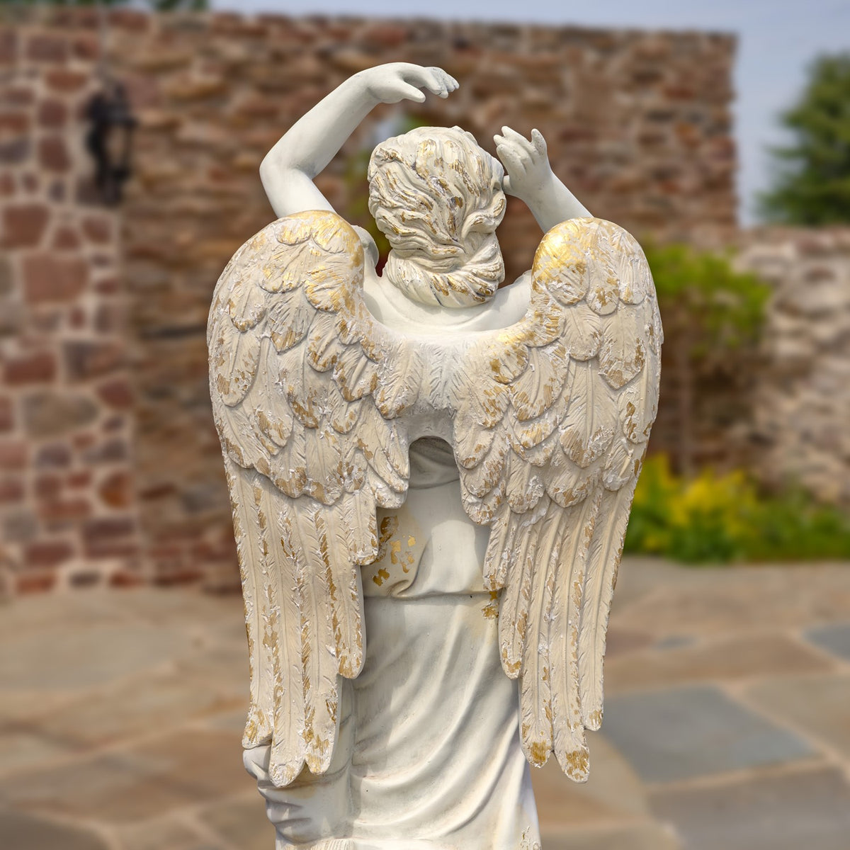 Back of the angel statue, showing layered wings and gathered hair.