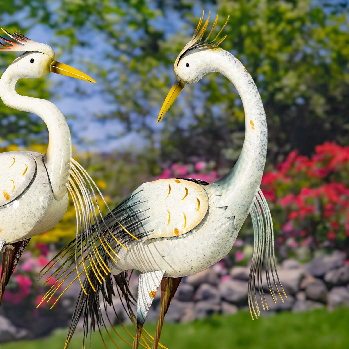 Two white heron figurines face each other, with curved necks, yellow beaks, and fine metal feather accents.
