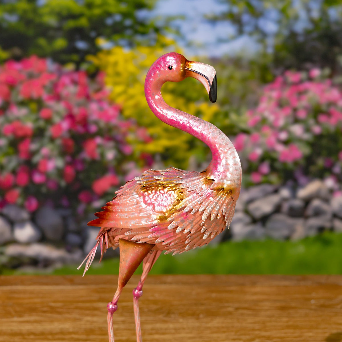 Pink flamingo figurine from the other side, with layered metal feathers and long slender legs.