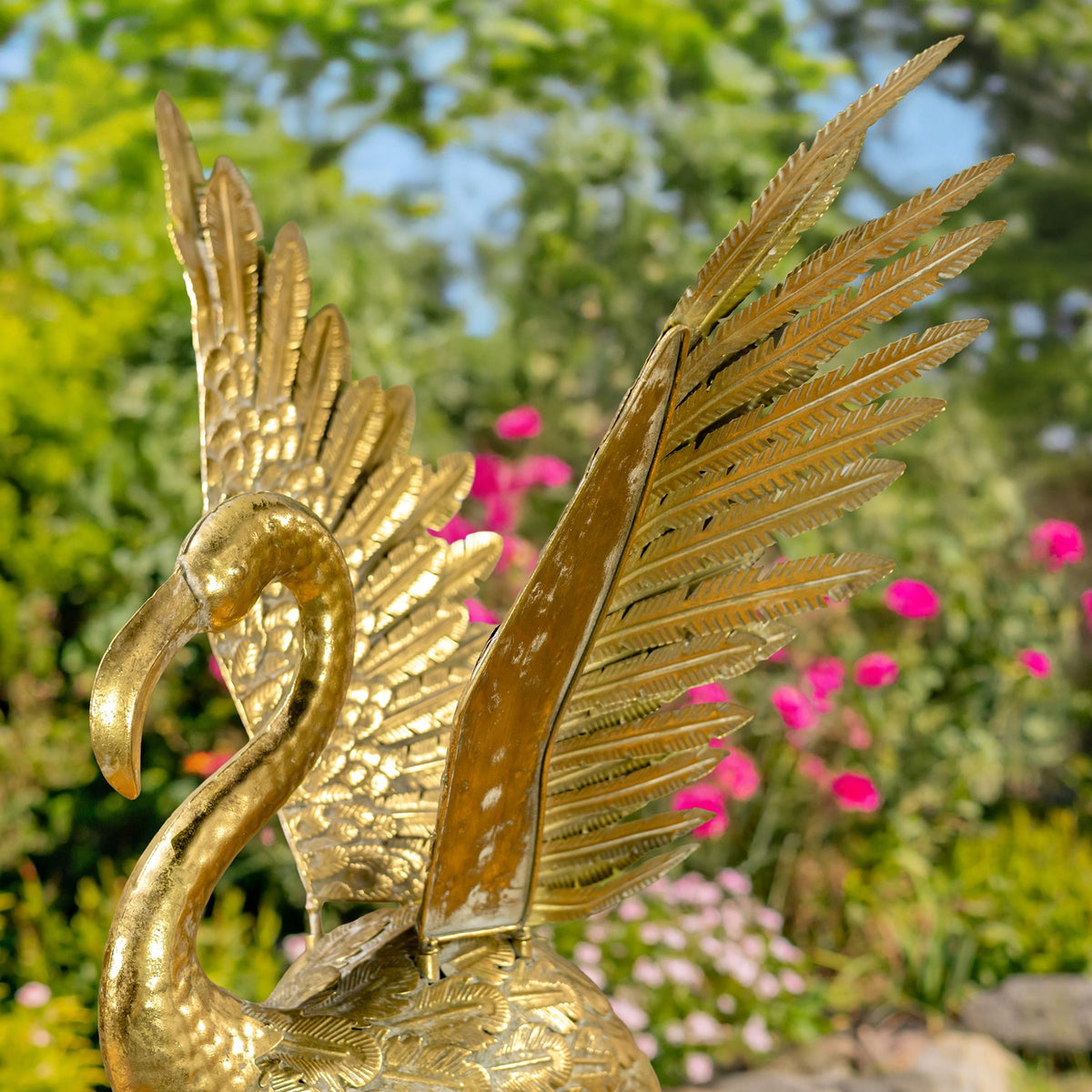 Close-up of the flamingo’s outstretched, feather-textured gold wings and curved neck.