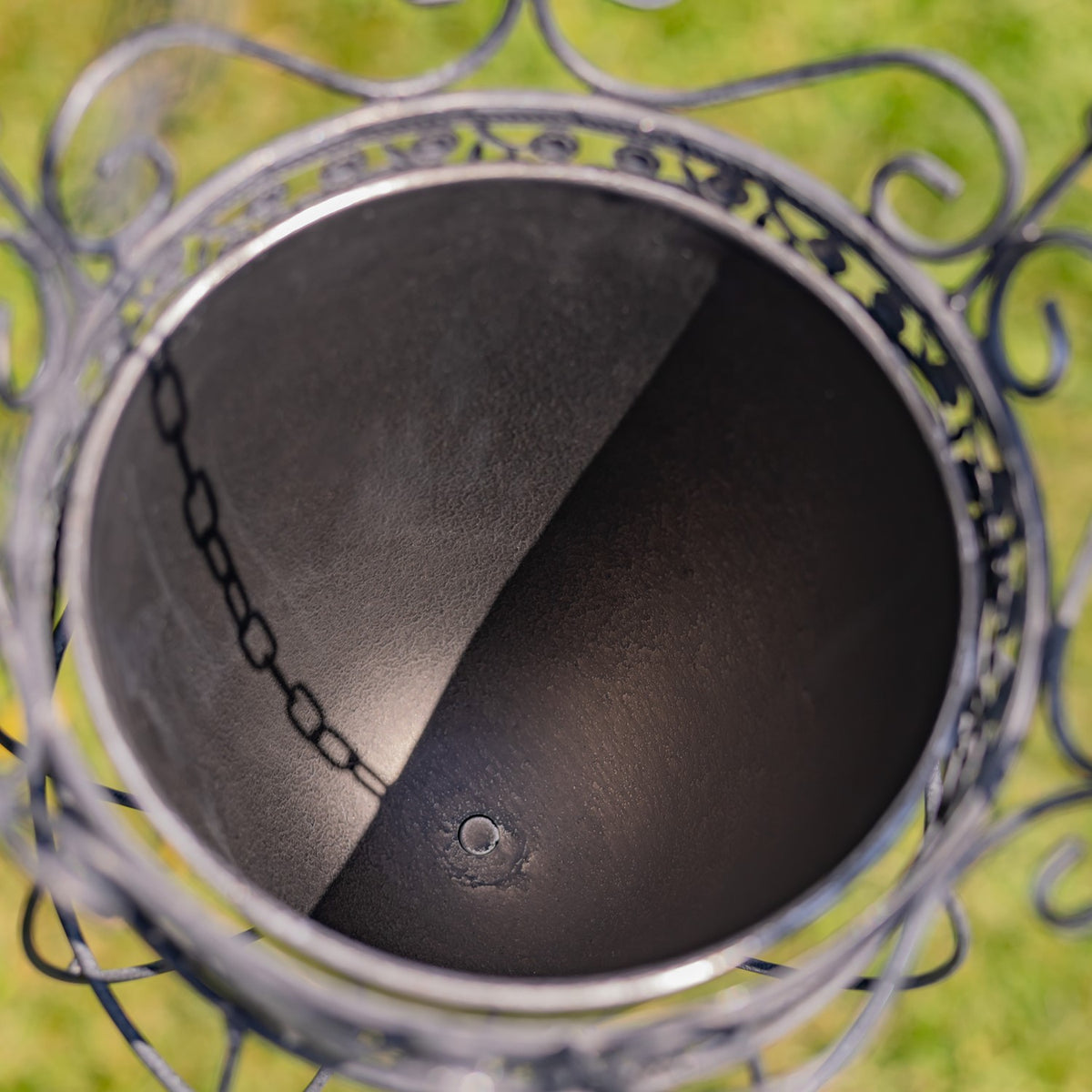 View down into the planter’s dark, empty inner pot, framed by its ornate metal rim.
