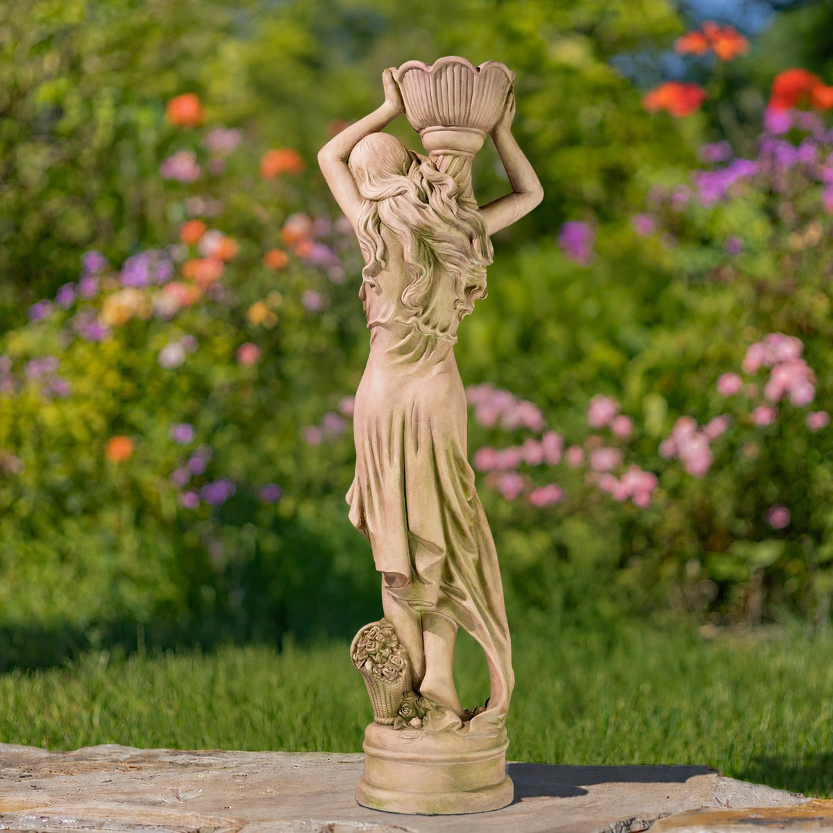 Full-length rear view of the statue holding a flower pot, standing on a round base in a garden.