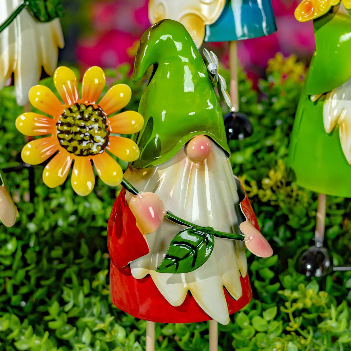 Green-hatted gnome holding a leafy stem beside an orange flower stake.