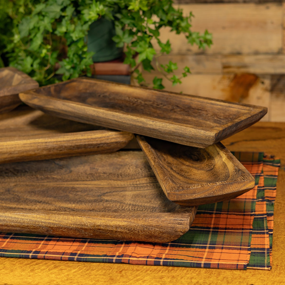 Wooden trays overlap in a rustic display, showing their varied sizes and textured grain.