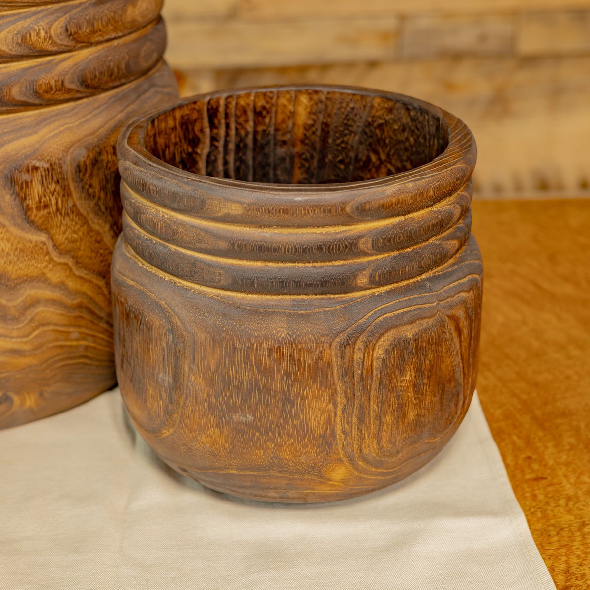 Close view of a smaller round bowl with a dark interior and carved rings around its rim.