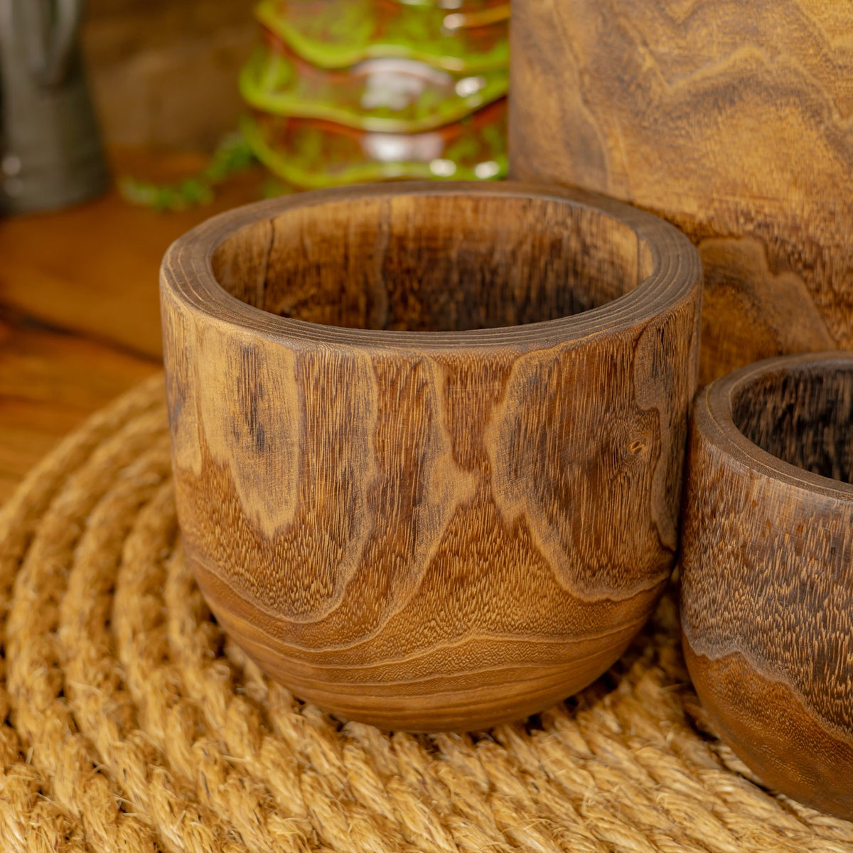 A round wooden bowl viewed from above, with a dark interior and prominent wavy grain.