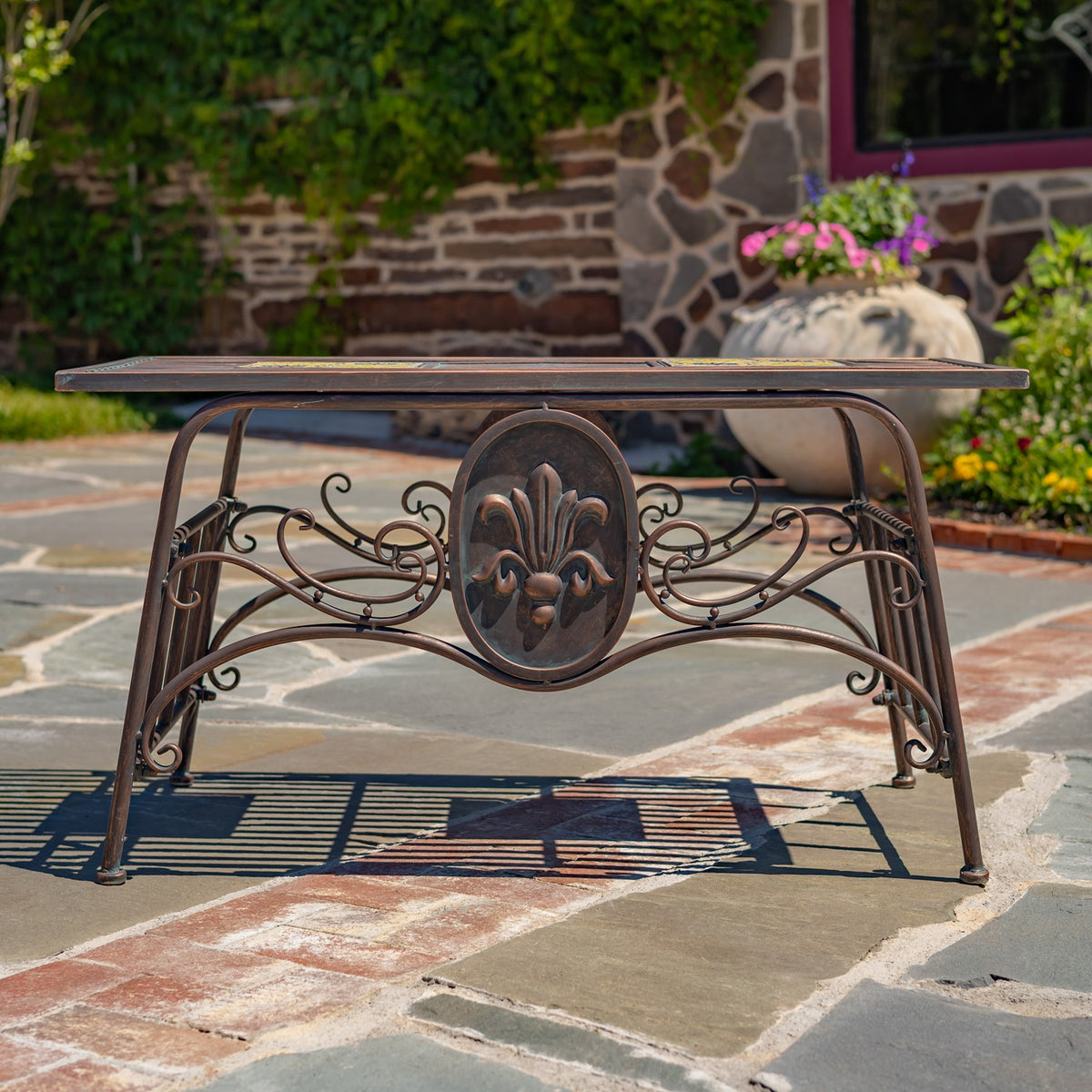 Side view of the table showing its thin rectangular top, curved metal legs, scrollwork, and central medallion.