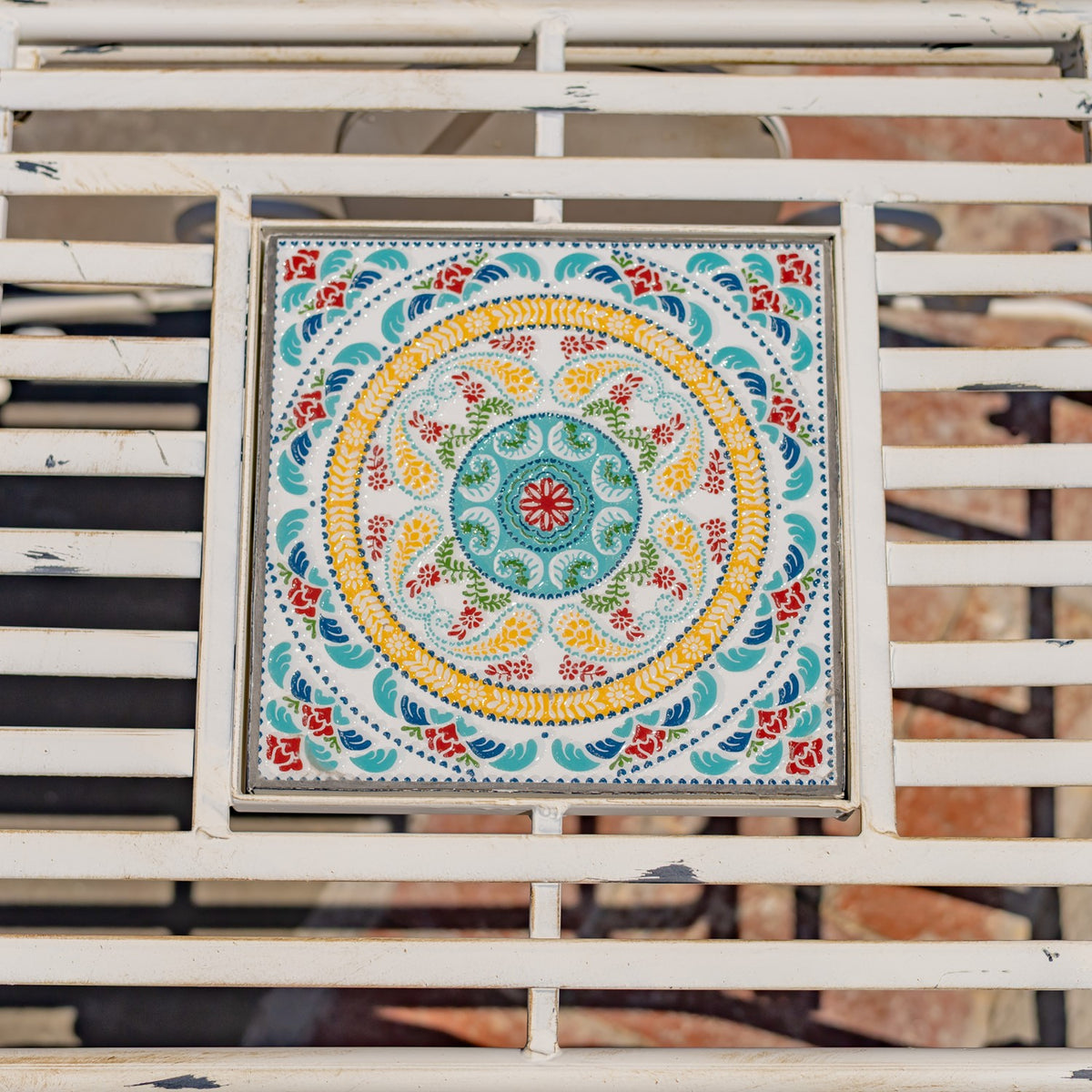 Overhead view of a colorful circular floral mosaic set into the chair’s ivory metal frame.